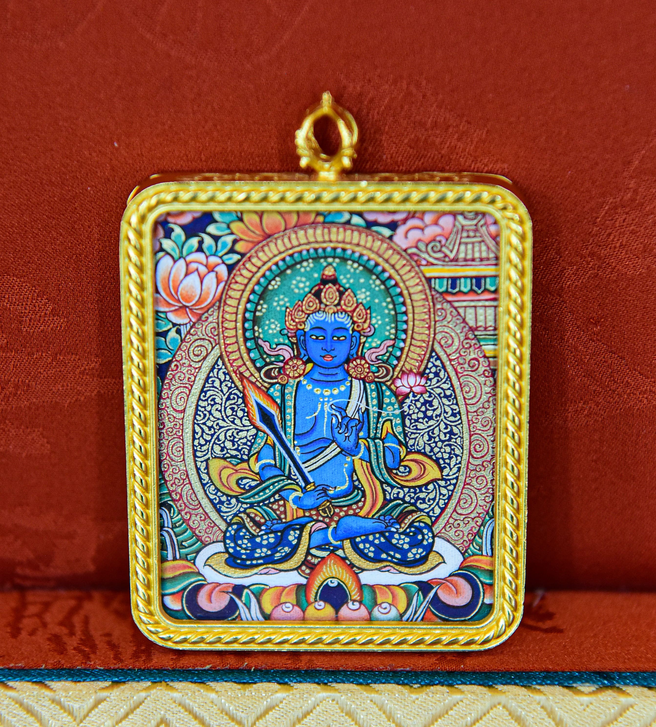 Blue miniature Thangka pendant with an intricate gold-toned frame